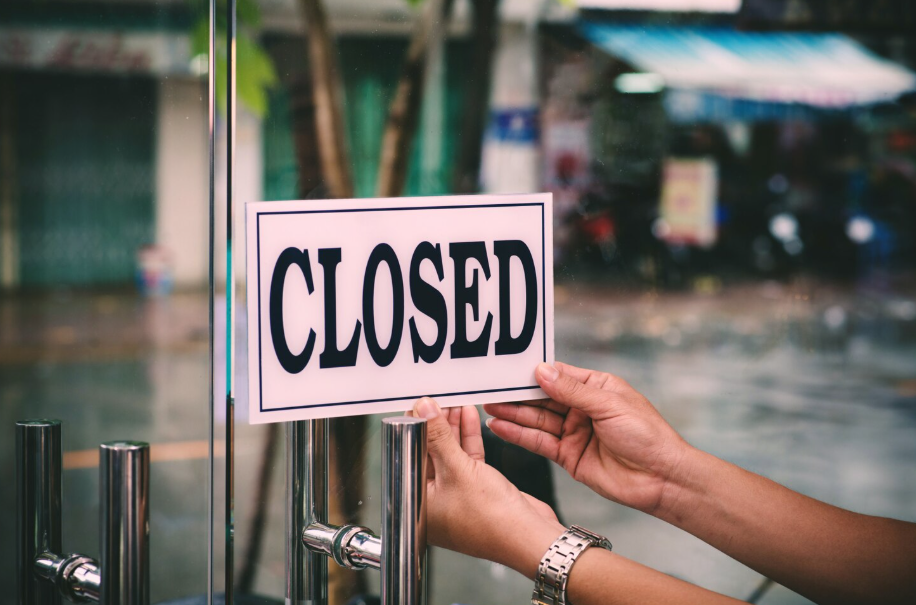 Business owner placing a closed sign on the door after legally dissolving their company.