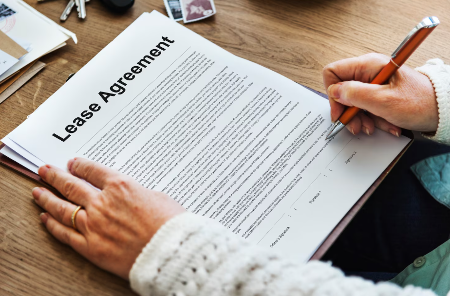 Person reviewing and signing a lease agreement before renting an apartment