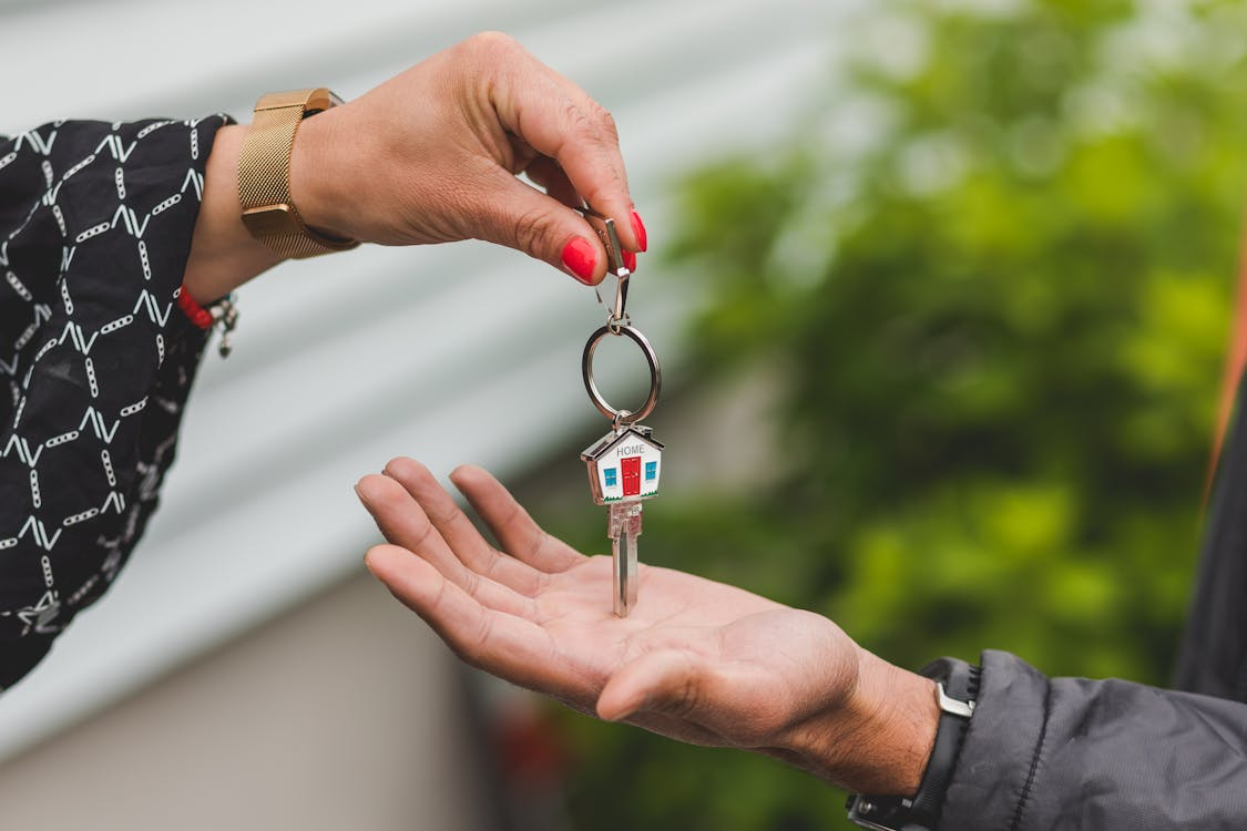 Landlord handing over house keys with a home-shaped keychain to tenant