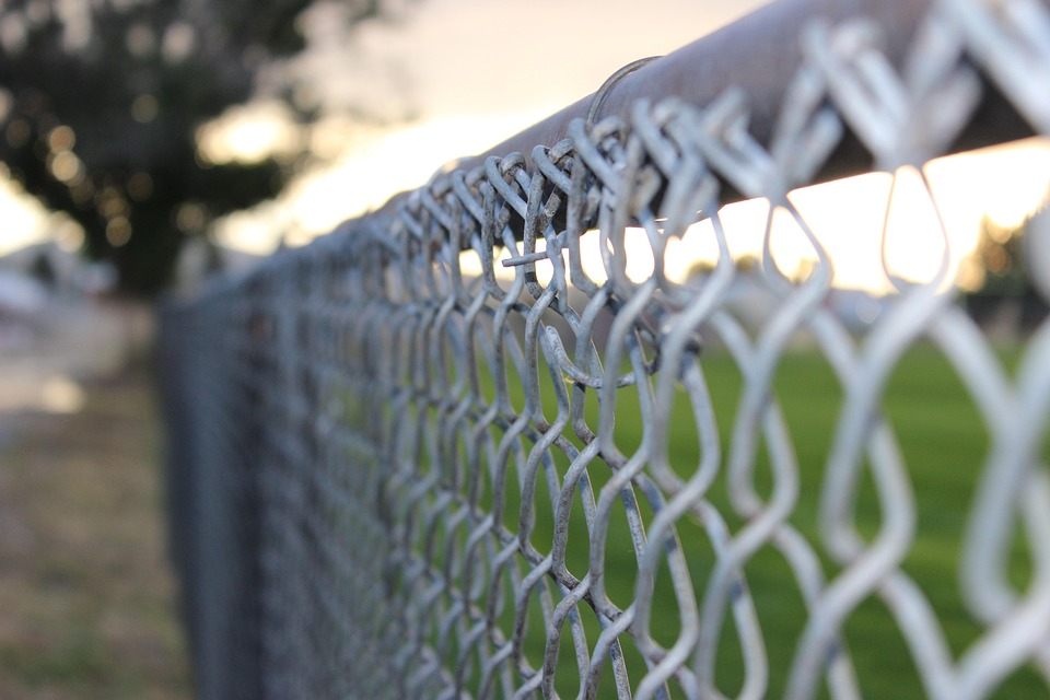 Close-up of a metal chain-link fence marking a property boundary between neighboring yards.