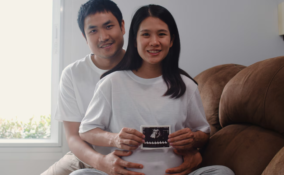 Expectant couple holding ultrasound photo during prenatal planning at home