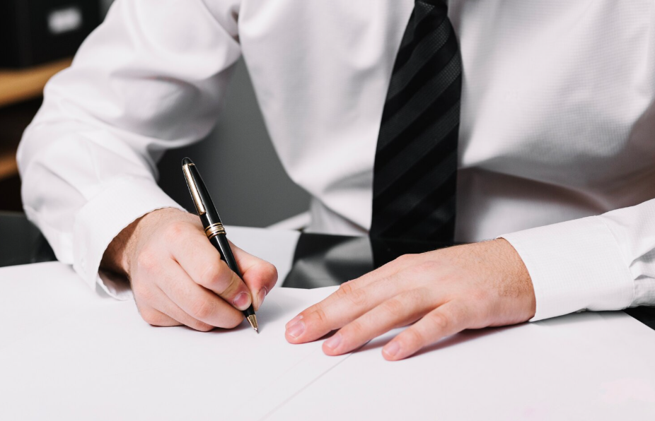 Close-up of a businessman signing a noncompete agreement at his desk.
