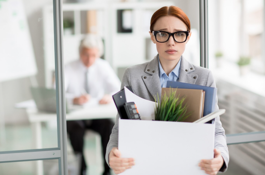 Upset employee carrying a box of belongings after being wrongfully fired from her job