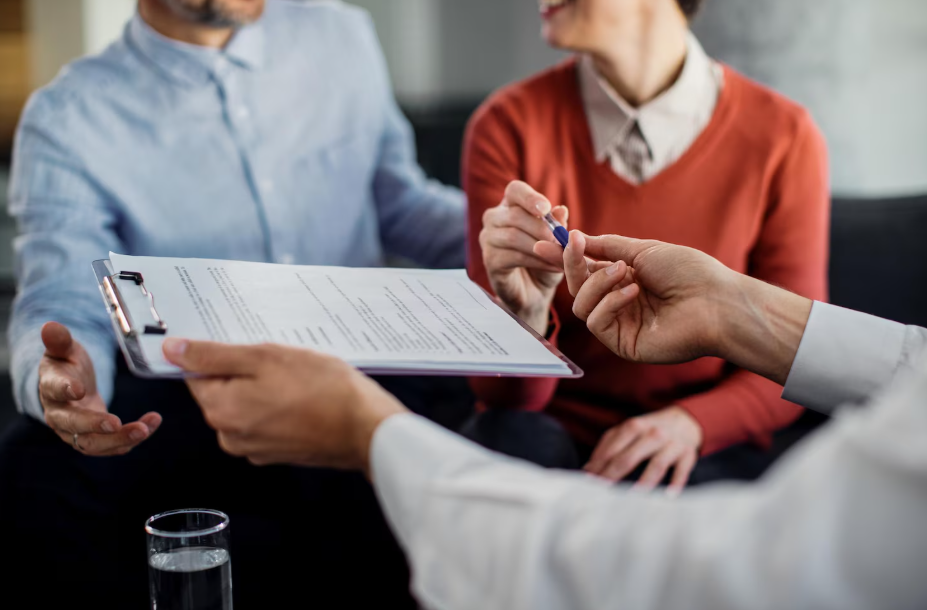 Couple reviewing and signing estate planning documents with an advisor