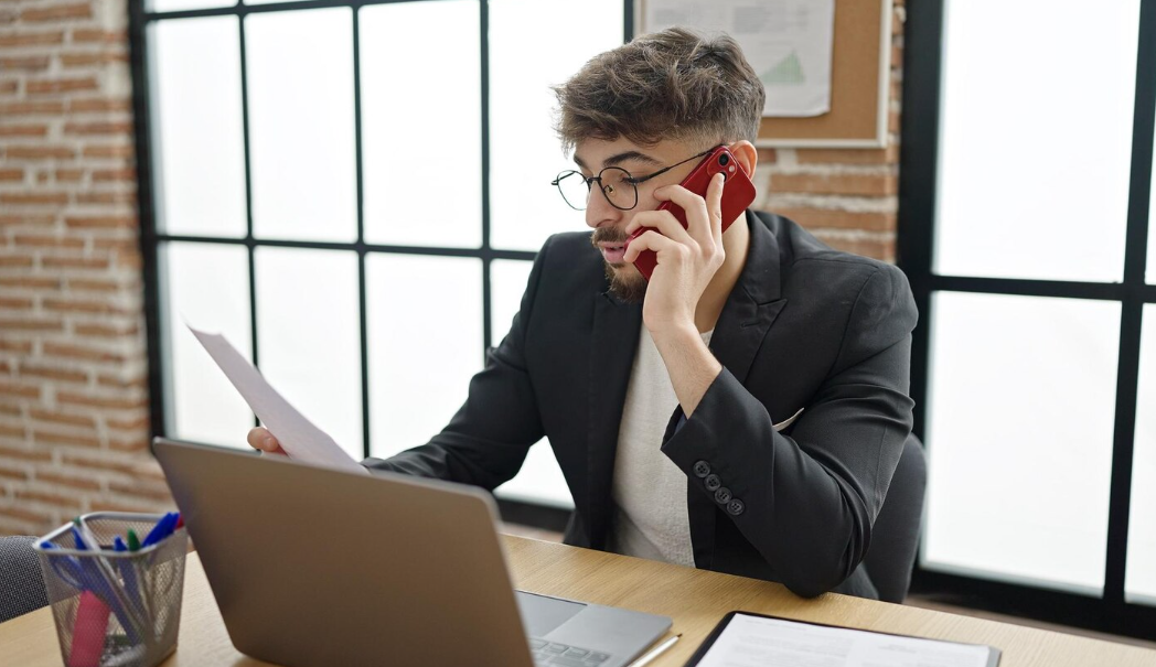 Man on phone reviewing a debt collection notice at his desk